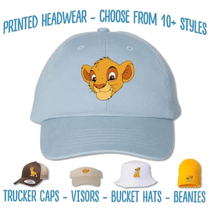May include: A light blue baseball cap with a cartoon image of Simba from The Lion King. The image shows Simba's face with a light brown mane. The text "PRINTED HEADWEAR - CHOOSE FROM 10+ STYLES" is at the top of the image. The text "TRUCKER CAPS - VISORS - BUCKET HATS - BEANIES" is at the bottom of the image. The image shows four different styles of hats with the same image of Simba.