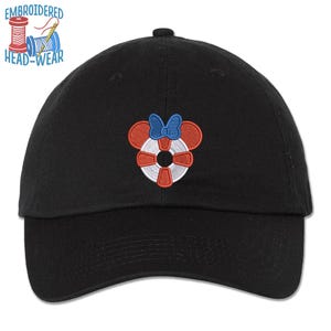 May include: Black baseball cap with an embroidered red, white, and blue life preserver with a blue bow on top. The text "EMBROIDERED HEAD-WEAR" is above the cap.