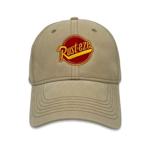 May include: A tan baseball cap with a red and yellow embroidered logo that says "Rust-eze".