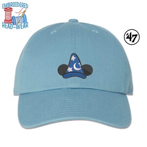 May include: A light blue baseball cap with an embroidered image of Mickey Mouse wearing a sorcerer's hat. The hat has a blue and white design with stars and a crescent moon. The cap is a 47 brand.