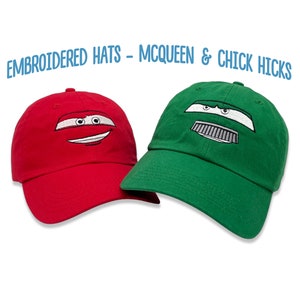 May include: Two embroidered baseball caps, one red and one green, featuring the faces of Lightning McQueen and Chick Hicks from the Disney Pixar Cars movie. The text "EMBROIDERED HATS - MCQUEEN & CHICK HICKS" is displayed above the caps.