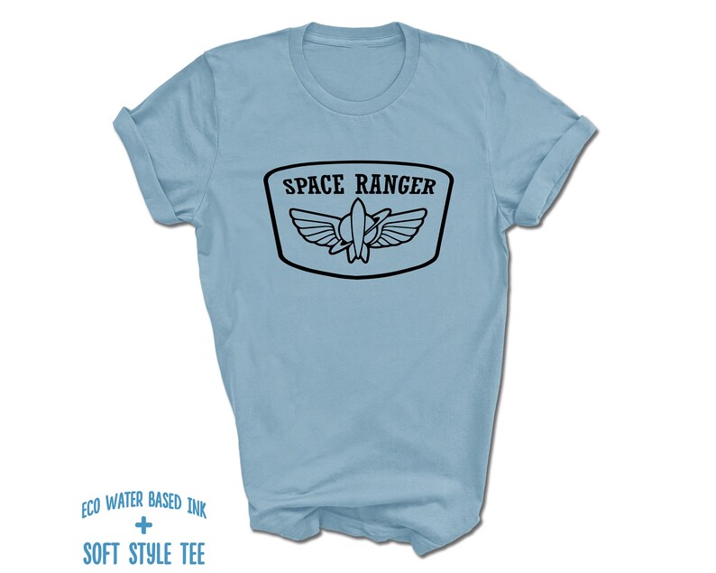May include: Light blue t-shirt with a black graphic of a space ranger logo. The logo says "Space Ranger" and features a rocket ship with wings.