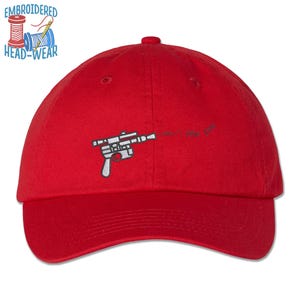 May include: Red baseball cap with an embroidered image of a blaster gun from the Star Wars franchise.