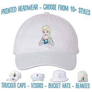 May include: White baseball cap with an embroidered image of a cartoon character with blonde hair and a blue dress. The text "PRINTED HEADWEAR - CHOOSE FROM 10+ STYLES" is at the top of the image. The text "TRUCKER CAPS - VISORS - BUCKET HATS - BEANIES" is at the bottom of the image.