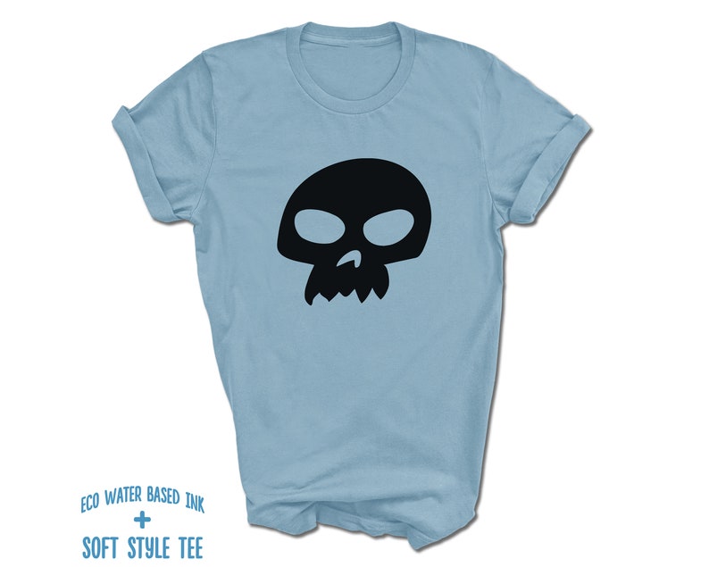 Pu&ograve; includere: Una t-shirt blu chiaro con una grafica di teschio nero. Il testo "ECO WATER BASED INK + SOFT STYLE TEE" &egrave; stampato sul fondo della t-shirt.