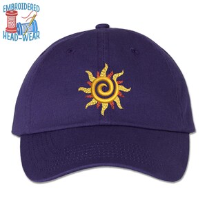 May include: A navy blue baseball cap with an embroidered sun design. The sun is yellow with red and orange accents.