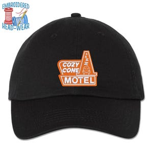 May include: A black baseball cap with an orange embroidered patch that says "Cozy Cone Motel" with a cartoon car and a "Zzz" above it.