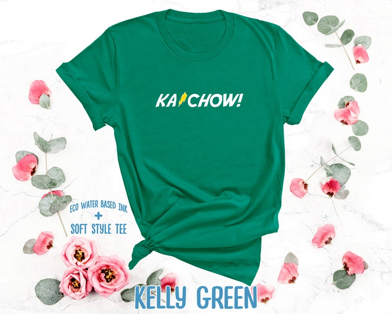 Op de afbeelding: Een kellygroen T-shirt met de tekst "KACHOW!" in geel met een bliksem-graphic. Het shirt is gemaakt met eco-water gebaseerde inkt en een zachte stijl tee.