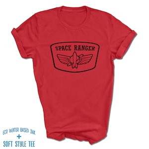 May include: Red t-shirt with a black graphic of a space ranger logo. The logo says "Space Ranger" and features a rocket ship with wings.