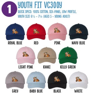 May include: A set of ten youth-sized baseball caps in various colors, each featuring an embroidered image of a cartoon tiger. The caps are labeled with their color names: Royal Blue, Red, Pink, Navy Blue, Light Pink, Khaki, Kelly Green, Grey, Baby Blue, Black, and White. The text "YOUTH FIT VC300Y" is displayed at the top of the image. The text "QUICK SPECS: 100% COTTON, SIX-PANEL, LOW PROFILE, YOUTH SIZE 6 1/2 - 7 1/4 (AGES 5 - YOUNG ADULT)" is displayed below the caps.