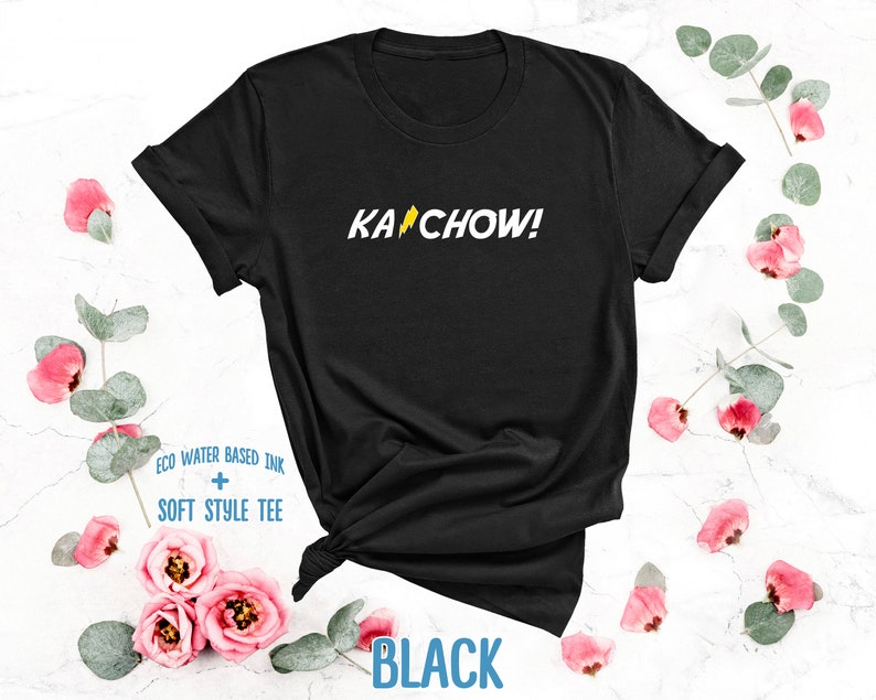 Op de afbeelding: Zwart T-shirt met een gele bliksem en de tekst "KACHOW!" gedrukt op de voorkant.
