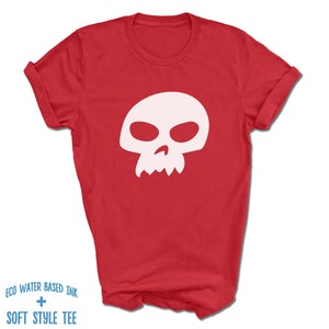 Pu&ograve; includere: Maglietta rossa con una grafica di teschio bianco. Il teschio ha un design semplice con due orbite e una piccola bocca.