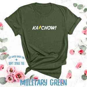 Op de afbeelding: Een groen T-shirt met de tekst "KACHOW!" in het geel gedrukt op de voorkant. Het shirt is gemaakt met milieuvriendelijke, watergebaseerde inkt en heeft een zacht, comfortabel gevoel.