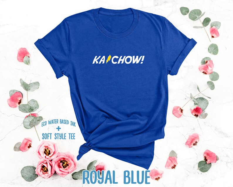 Op de afbeelding: Een koninklijk blauw T-shirt met de tekst "KACHOW!" in geel met een bliksem-afbeelding. Het T-shirt is gemaakt met milieuvriendelijke, watergebaseerde inkt en een zachte stijl.