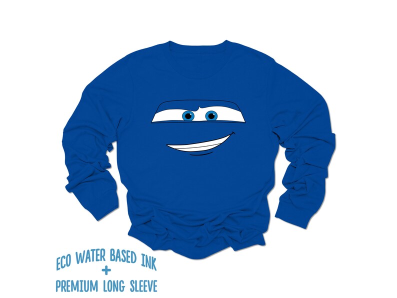 May include: A royal blue long-sleeved shirt with a cartoon face of a car with blue eyes and a white smile.