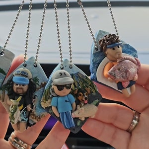 May include: Four handmade polymer clay charms featuring people holding fish. Each charm is attached to a silver chain and has a painted background.
