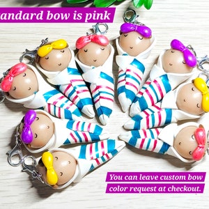 May include: Nine colorful handmade baby doll keychains with striped clothing and bows. The standard bow color is pink. You can leave a custom bow color request at checkout.