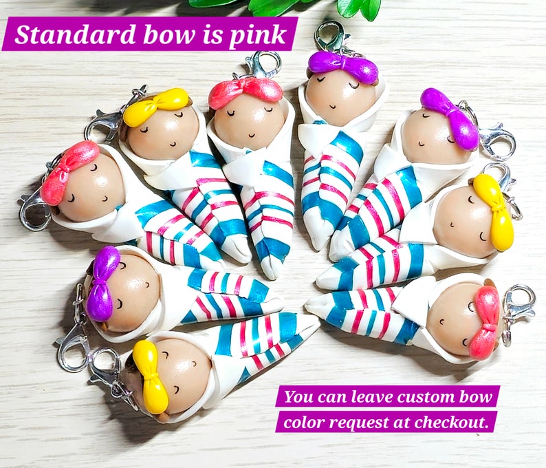 May include: Nine colorful handmade baby doll keychains with striped clothing and bows. The standard bow color is pink. You can leave a custom bow color request at checkout.