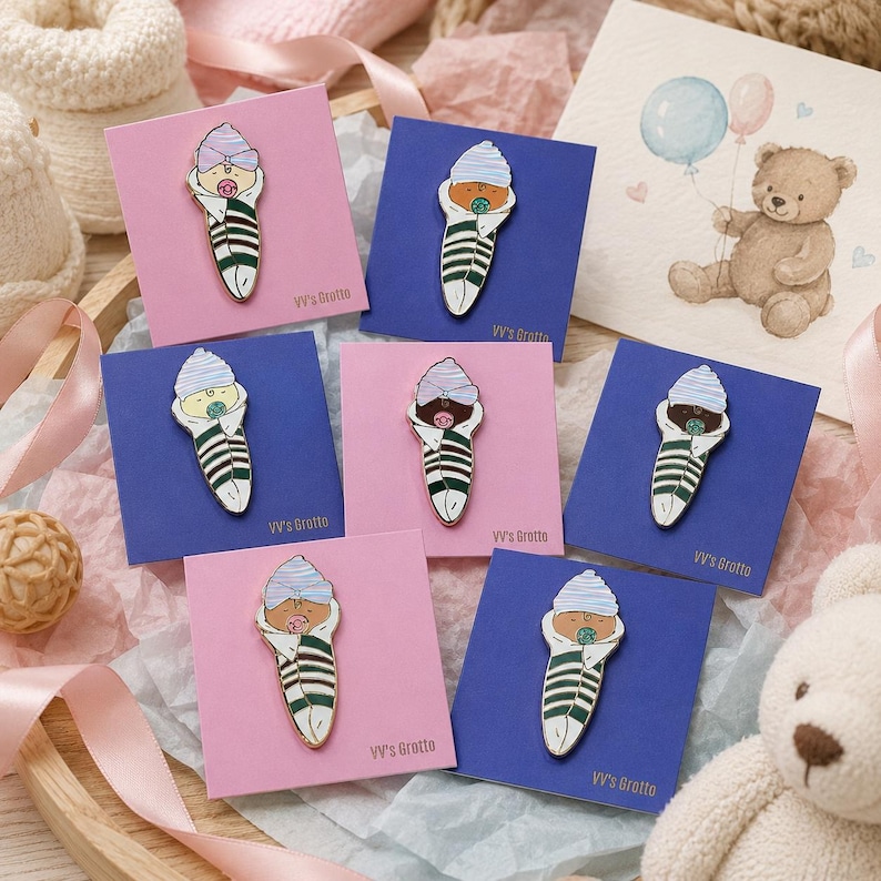Pode incluir: Sete pins de esmalte com um beb&eacute; enrolado numa manta branca com riscas verde-escuras, usando um gorro &agrave;s riscas azuis ou roxas e uma chupeta. Cada pin est&aacute; montado num cart&atilde;o quadrado cor-de-rosa ou azul com a etiqueta VV's Grotto.