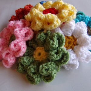 May include: A collection of crocheted flowers in various colors, including pink, yellow, green, white, and blue. The flowers are all different sizes and shapes, and they are arranged in a cluster.