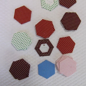 May include: A collection of 10 hexagon-shaped fabric pieces with polka dot patterns in red, white, green, blue, and brown.