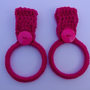 May include: Two pink crocheted towel rings with pink buttons.