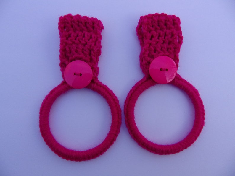 May include: Two pink crocheted towel rings with pink buttons.