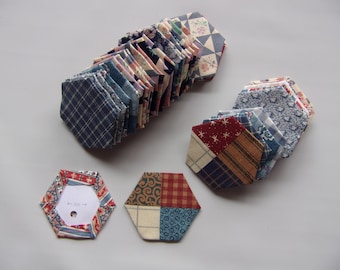 May include: A stack of 18 hexagon-shaped fabric pieces in various blue, red, white, and brown patterns. There are three additional hexagon-shaped fabric pieces with a 3-inch measurement marked on one of them.