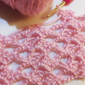 May include: Pink crocheted fabric with a delicate, openwork pattern. The fabric is made with a fine yarn and has a soft, airy texture.