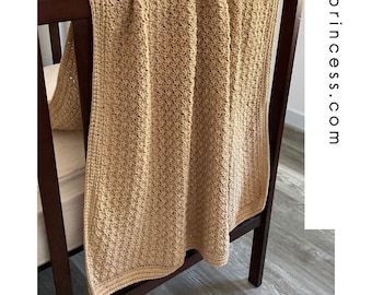 May include: A crocheted baby blanket in a neutral beige color, draped over a wooden crib. The blanket has a delicate stitch pattern and is perfect for a nursery.