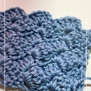 May include: Close-up of a blue crocheted fabric with a textured pattern. The fabric is made with a single strand of yarn and has a soft, fluffy texture.