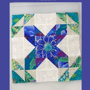 May include: A colorful quilt block with a floral design at the center. The block features a blue flower, surrounded by teal, purple, and white patterned fabric. Text at the top reads "Summer Winds Variation Nine Patch Quilt Block Pattern". Finished sizes are 9", 12", and 15".