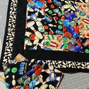 Peut inclure: Trois dessous-de-verre en tissu noir et blanc sur le thème du bowling. Les dessous-de-verre présentent des quilles de bowling, des boules de bowling et le texte "Retro Lanes".