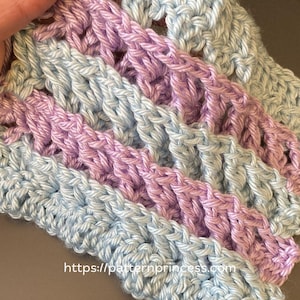 Può includere: Un campione di tessuto lavorato all'uncinetto con un motivo a punto 3D ZigZag Waffle a strisce alternate di filato azzurro e viola chiaro. Il testo 3D ZigZag Waffle e l'URL https://patternprincess.com sono visibili nell'immagine.