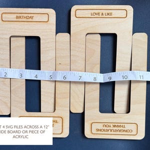 May include: Four light-colored wooden U-shaped cutouts arranged in a nested pattern. Each piece features engraved text including BIRTHDAY, LOVE & LIKE, and THANK YOU CONGRATULATIONS. A white measuring tape shows a width of approximately 12 inches.