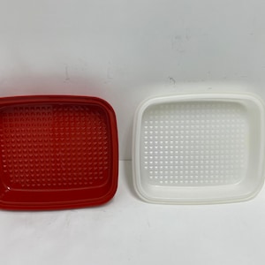 May include: Two square plastic containers with textured bottoms. One container is red and the other is white.