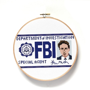 Könnte beinhalten: Ein weißer Kreuzstich-Stickrahmen mit einem blauen und weißen FBI-Abzeichen-Design. Das Abzeichen enthält den Text "Department of Investigation", "FBI", "Special Agent" und eine Unterschrift. Im oberen rechten Eck befindet sich ein pixeliertes Bild eines Mannes im Anzug.