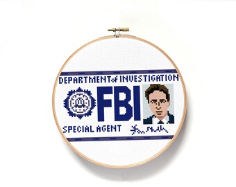 May include: A white cross-stitch embroidery hoop with a blue and white FBI badge design. The badge includes the text "Department of Investigation", "FBI", "Special Agent", and a signature. A pixelated image of a man in a suit is in the upper right corner.