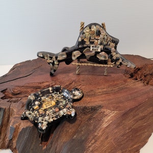 May include: Two decorative, black, resin turtle and sailfish figurines with a mosaic of iridescent seashells. The turtle has a small dish on its back. Both figurines have the words "Myrtle Beach" on them.