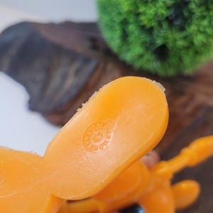 May include: Orange plastic toy figure with a circular logo on the bottom that reads "Made in Hong Kong".