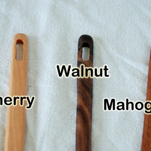 May include: Three wooden dowels with a hole in the center. The dowels are labeled "Cherry", "Walnut", and "Mahogany".