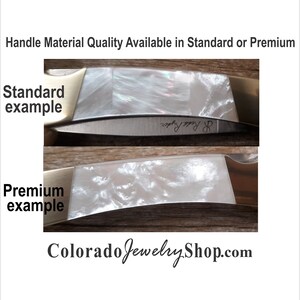 May include: Close-up of two knife handles showing the difference between standard and premium materials. The standard handle is a white pearlescent material with a subtle shimmer. The premium handle is a white pearlescent material with a more pronounced swirl pattern. The text "raphy ppy R" is visible on the standard handle. The text "Colorado Jewelry Shop.com" is visible at the bottom of the image.