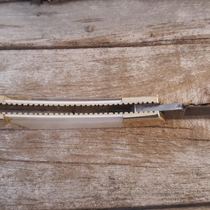May include: A closed pocket knife with a gold handle and a silver blade. The knife is open and the blade is visible.