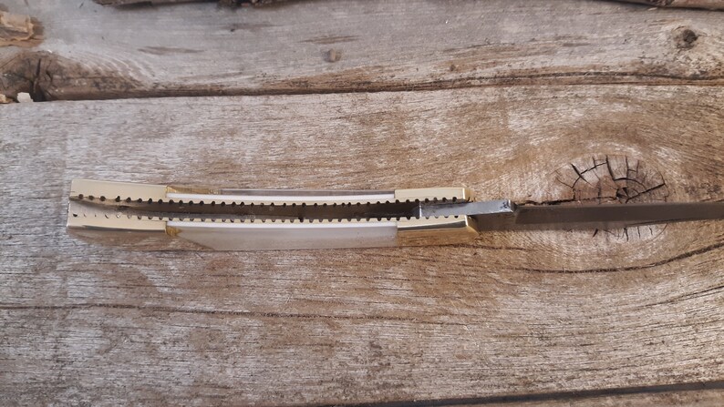 May include: A closed pocket knife with a gold handle and a silver blade. The knife is open and the blade is visible.