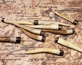 May include: A collection of eight antler tips with brown and black resin accents. The antler tips are various sizes and shapes. The antler tips are arranged on a brown background.