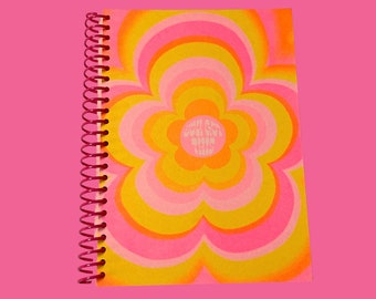 May include: A pink and yellow spiral bound notebook with a flower design and the text "You Got This, Boo Boo, Keep Going" in white.