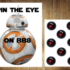 May include: A white and orange BB-8 Star Wars character with a hole cut out for a pin the eye game. The text "Pin the Eye on BB8" is printed on the game board. There are 7 red eyes on a separate sheet of paper.