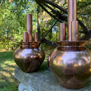 Peut inclure: Deux pots en cuivre avec des tuyaux en cuivre qui dépassent du haut. Les pots sont posés sur une surface en pierre.