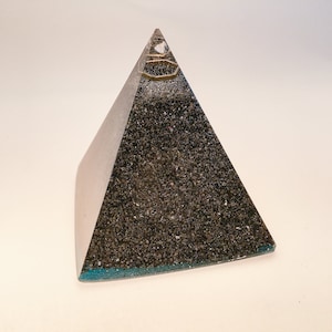 May include: A black pyramid-shaped crystal with a gold-colored top and a teal-colored base.