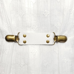 White leather cinch clip w/ bronze tone clips. Dress clip, jacket clip, shirt clip, sweater clip, skirt clip, cloak clip, DIY tailoring.